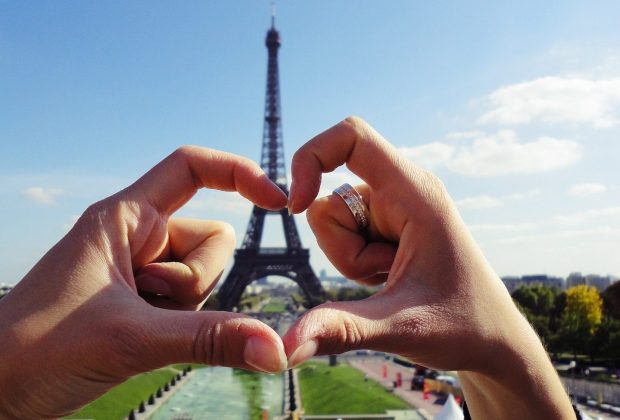 Heart shaped hands around the Eiffel Tower in Paris